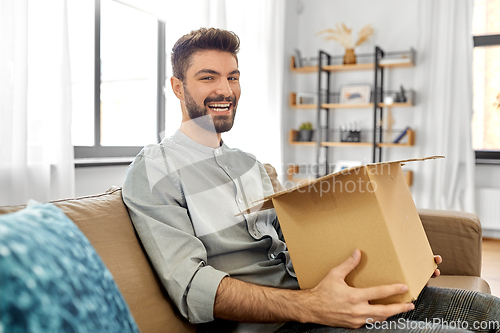 Image of happy smiling man opening parcel box at home