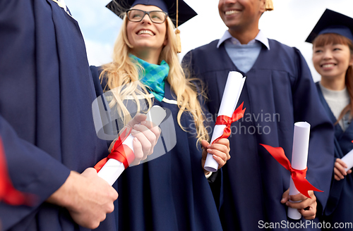 Image of graduate students in mortar boards with diplomas