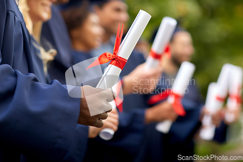 Image of graduate students in mortar boards with diplomas