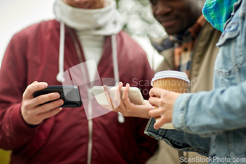 Image of friends with smartphone and coffee outdoors