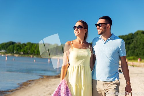 Image of happy couple with picnic basket walking on beach