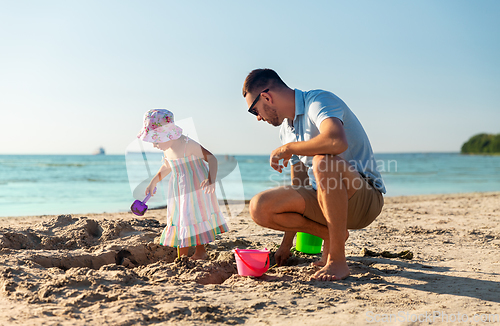 Image of father and daughter playing with toys on beach