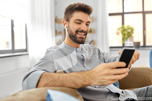 Image of man in earphones listening to music on smartphone