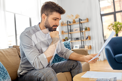 Image of stressed man with bills at home