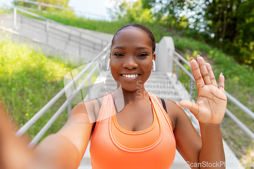 Image of happy african woman with earphones taking selfie