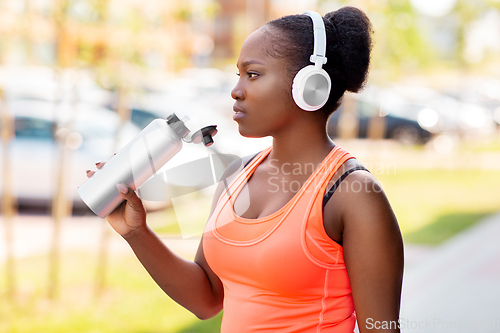 Image of african american woman drinking water after sports