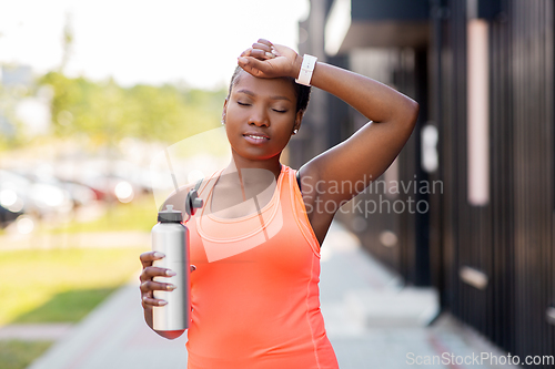 Image of tired african american woman with bottle of water