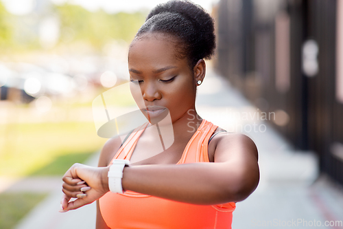 Image of african woman with smart watch doing sports