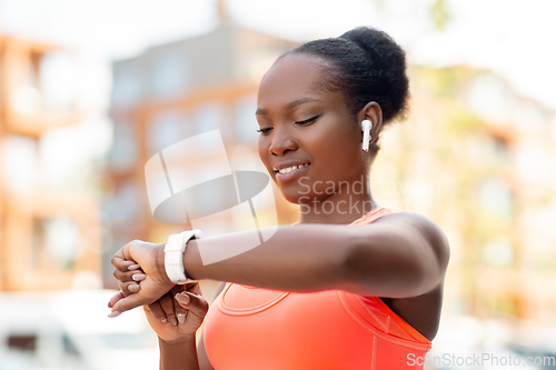 Image of happy african woman with earphones and smart watch