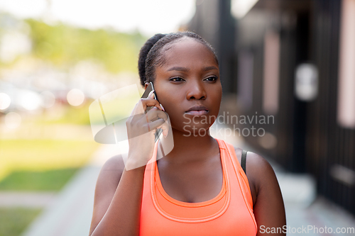 Image of sporty african woman calling on smartphone in city