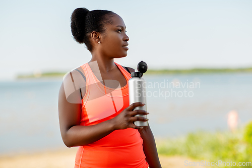 Image of african american woman drinking water from bottle