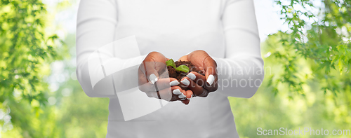 Image of woman holding plant growing in handful of soil
