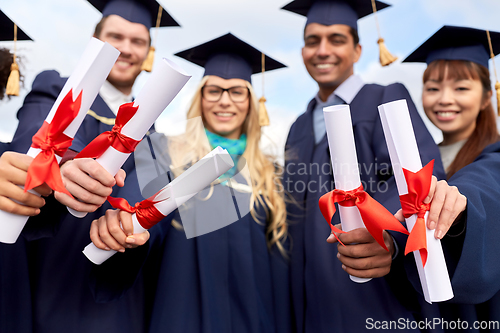 Image of graduate students in mortar boards with diplomas