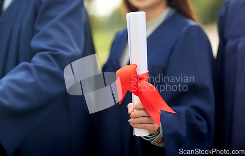 Image of graduate students in mortar boards with diplomas