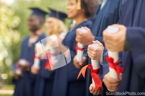 Image of graduate students in mortar boards with diplomas