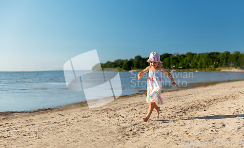 Image of happy baby girl running on summer beach