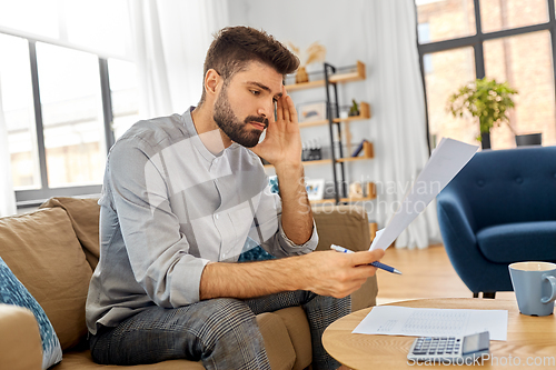 Image of stressed man with bills at home