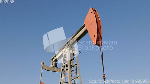 Image of Operating oil and gas well in oil field, profiled against the blue sky