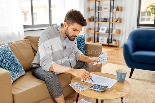 Image of man with money and calculator filling papers