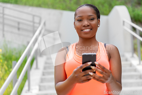 Image of smiling sporty african woman using smartphone