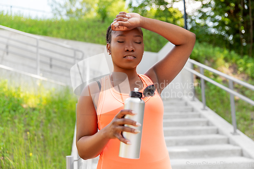 Image of tired african american woman with bottle of water