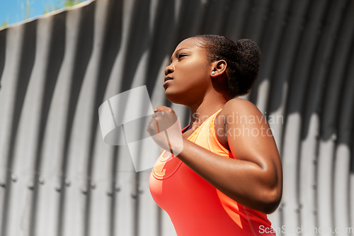 Image of young african american woman running in tunnel