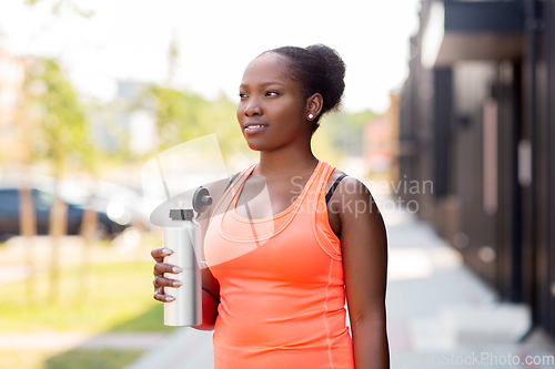 Image of african american woman drinking water from bottle