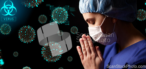 Image of female doctor or nurse in face mask praying