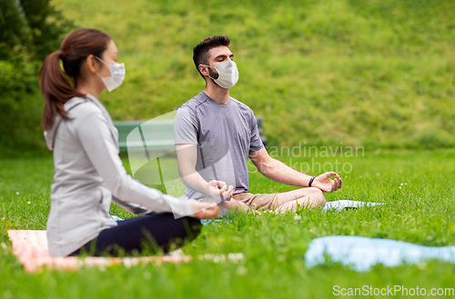 Image of people in masks meditating at summer park