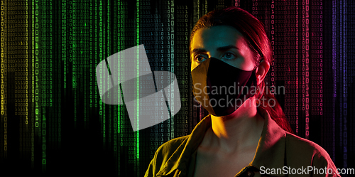 Image of female hacker in black mask over binary code