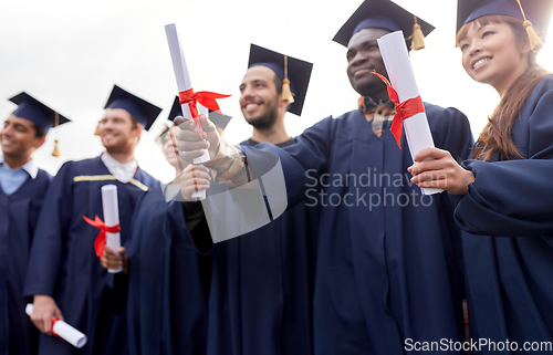 Image of graduate students in mortar boards with diplomas