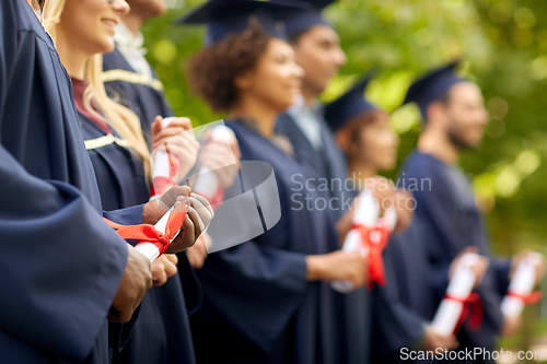 Image of graduate students in mortar boards with diplomas