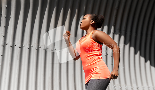 Image of young african american woman running in tunnel