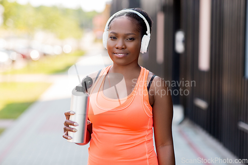 Image of african american woman drinking water after sports