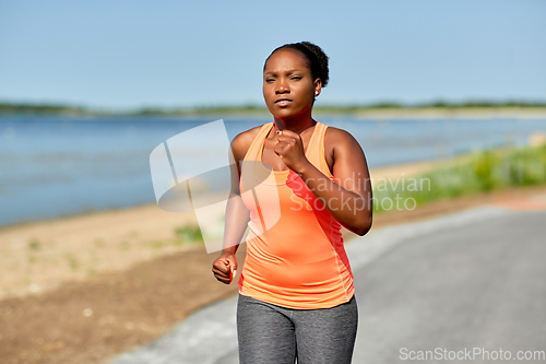 Image of young african american woman running at seaside