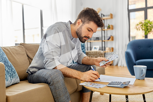 Image of man with money and calculator filling papers