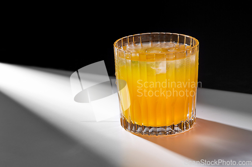 Image of glass of orange juice with ice on table