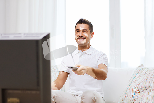 Image of smiling middle aged man with vitiligo watching tv