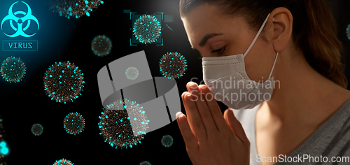 Image of sick young woman in protective face mask praying