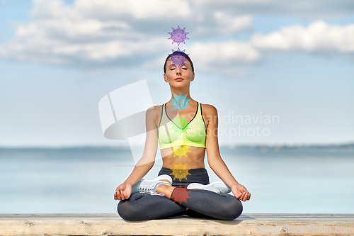 Image of woman meditating in lotus pose with seven chakras