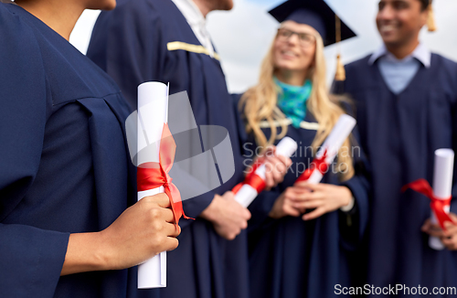 Image of graduate students in mortar boards with diplomas