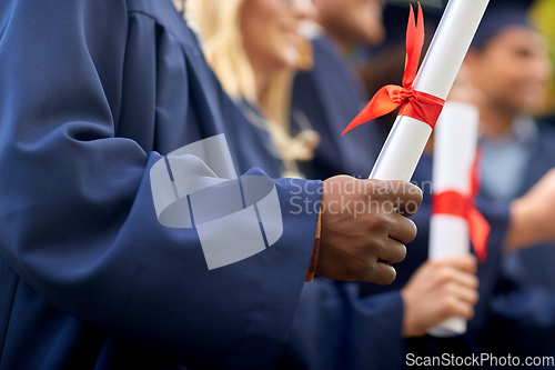 Image of graduate students in mortar boards with diplomas