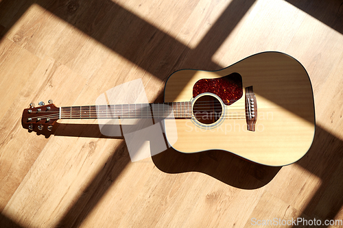 Image of close up of acoustic guitar on wooden floor