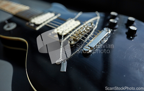 Image of close up of bass guitar with metallic pendant