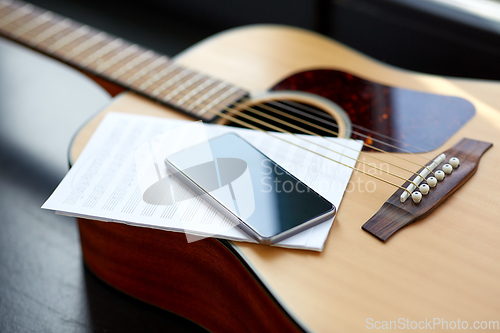 Image of close up of guitar, music book and smartphone