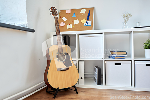 Image of close up of acoustic guitar on stand at home