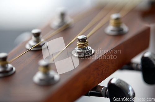 Image of close up of acoustic guitar head with pegs