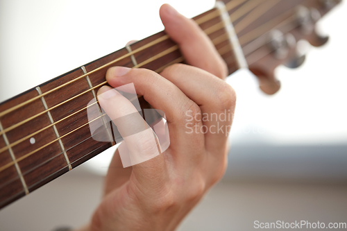 Image of close up of hand with guitar neck playing music