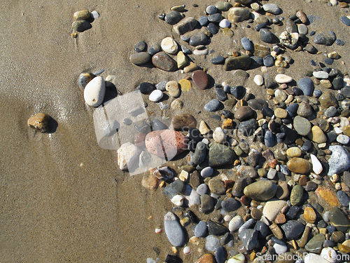 Image of Wet sea pebbles on the sand