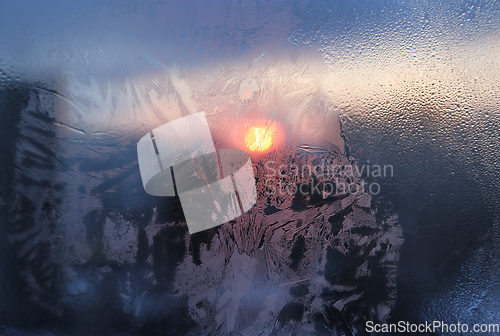 Image of Ice pattern and water drops on glass on a sunny winter morning